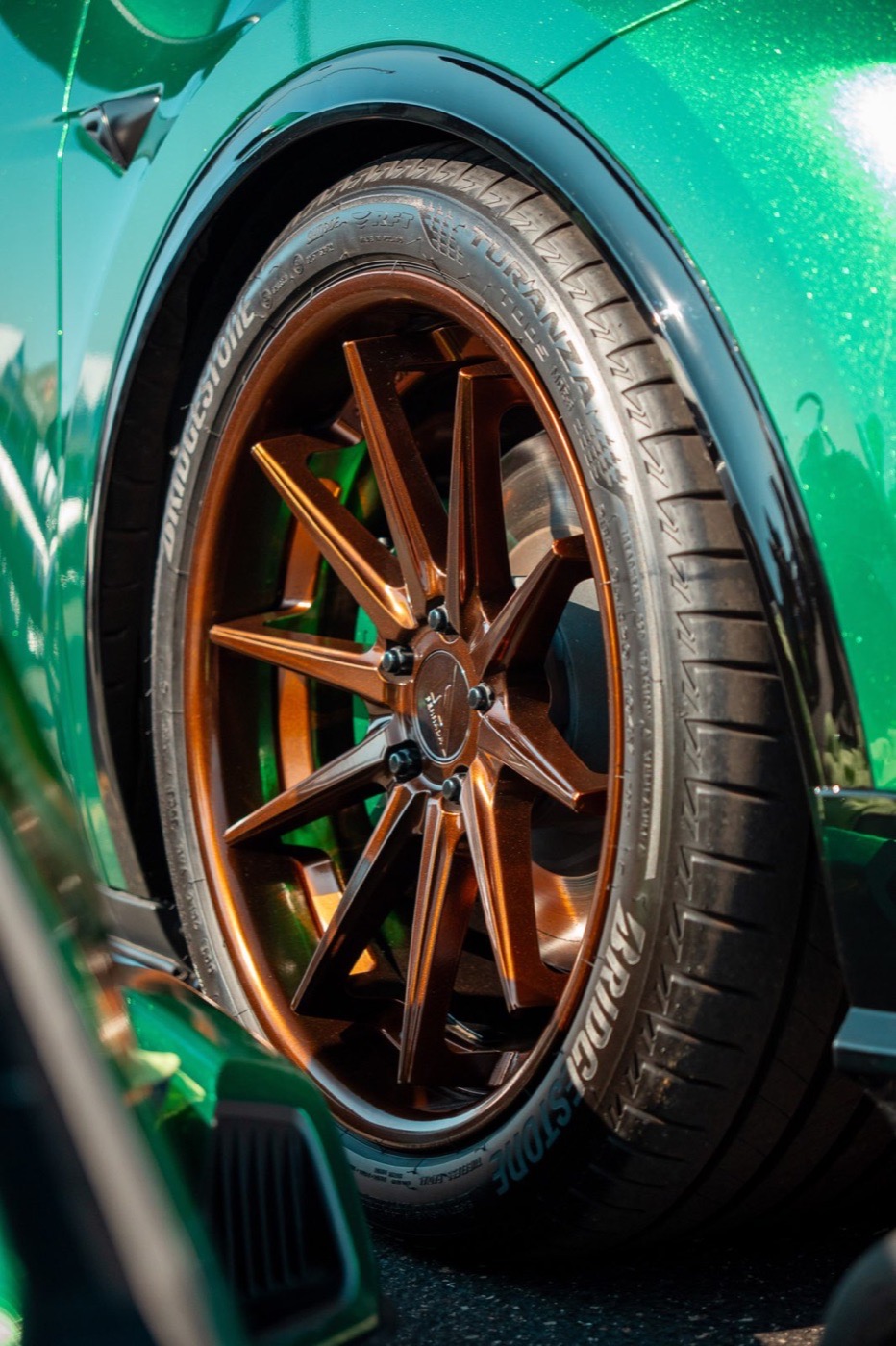 Close-up of a bronze wheel on a green performance car