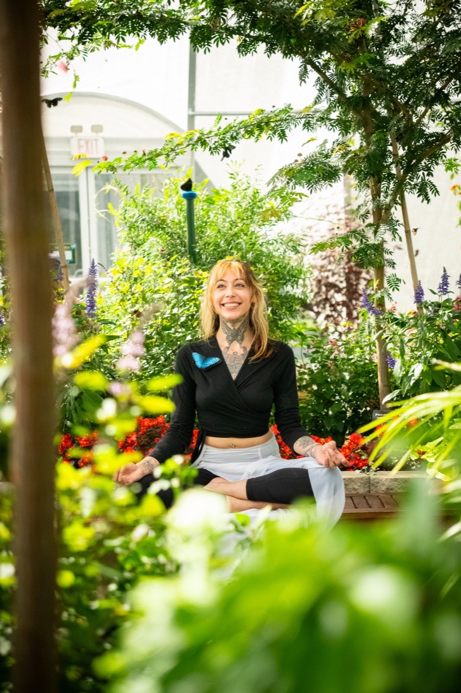 Portrait of a woman seated in a bright garden surrounded by plants