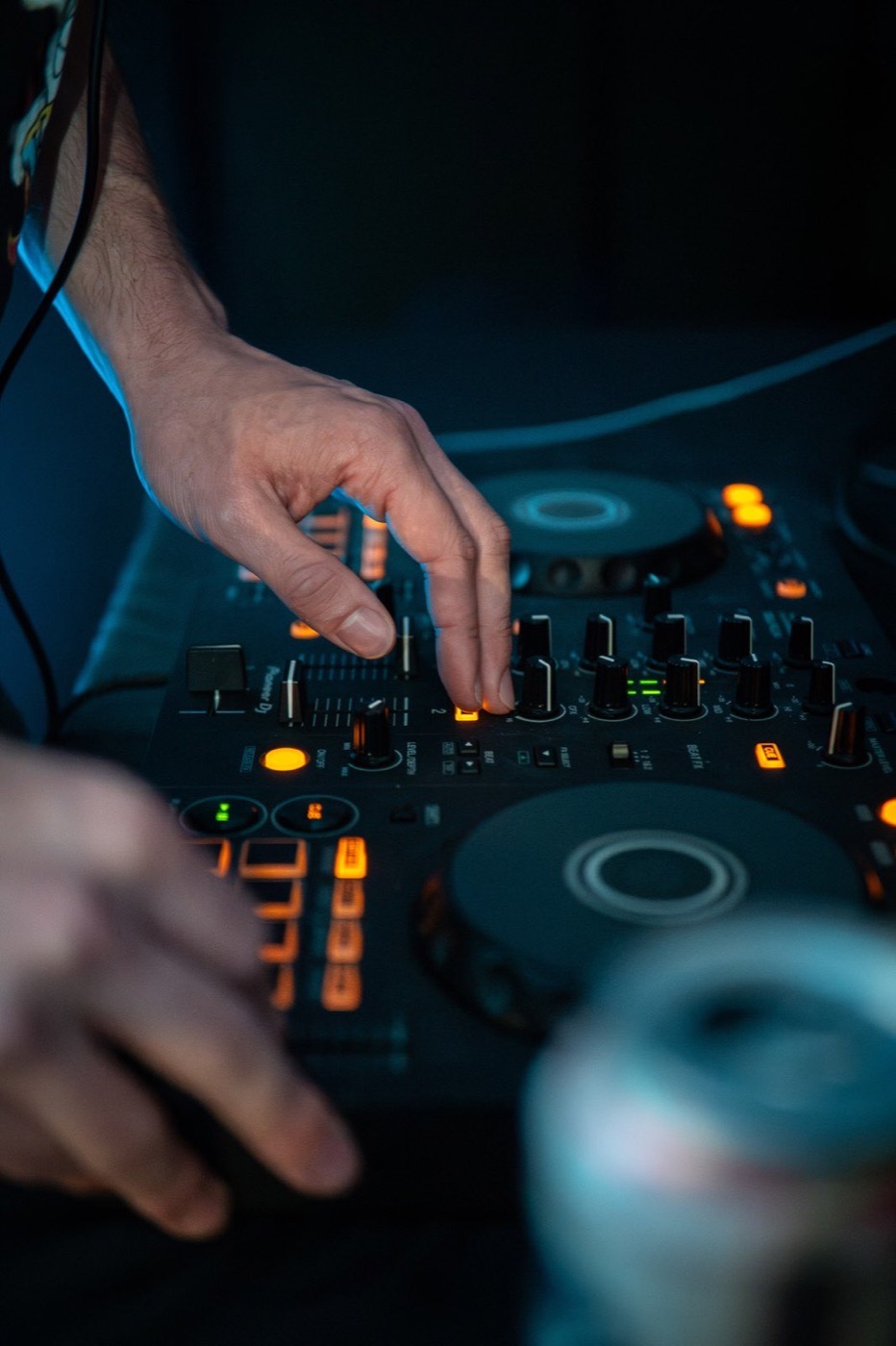 Close-up of hands working a DJ mixer in low light
