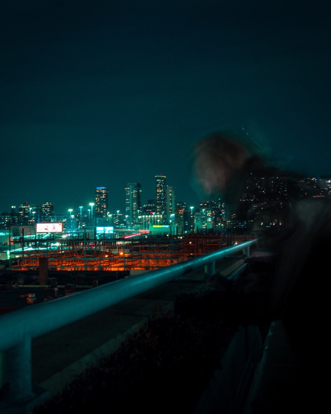 Blurred figure on a rooftop with a glowing city skyline in the background
